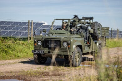 Lurcher vehicle being driven past a field of solar panels