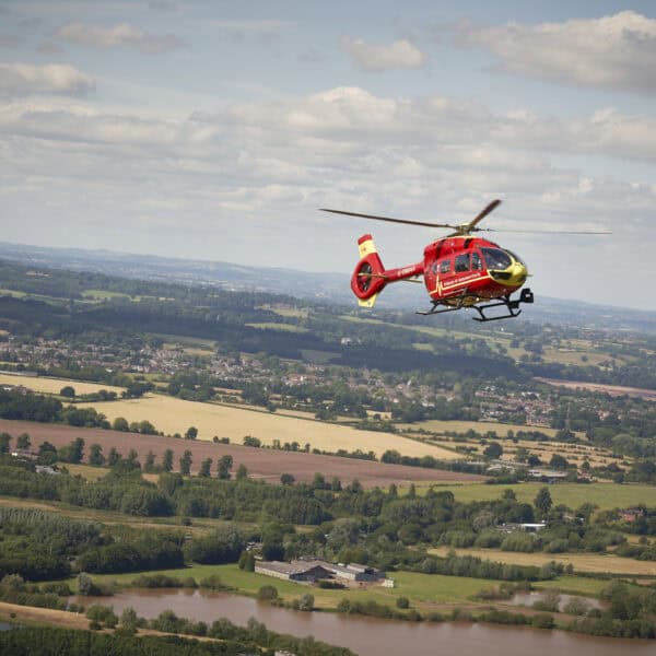 Midlands Air Ambulance red helicopter flying over countryside