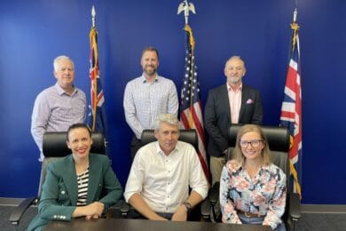 The executive team of H&B Defence in front of the flags of Australia, USA and UK