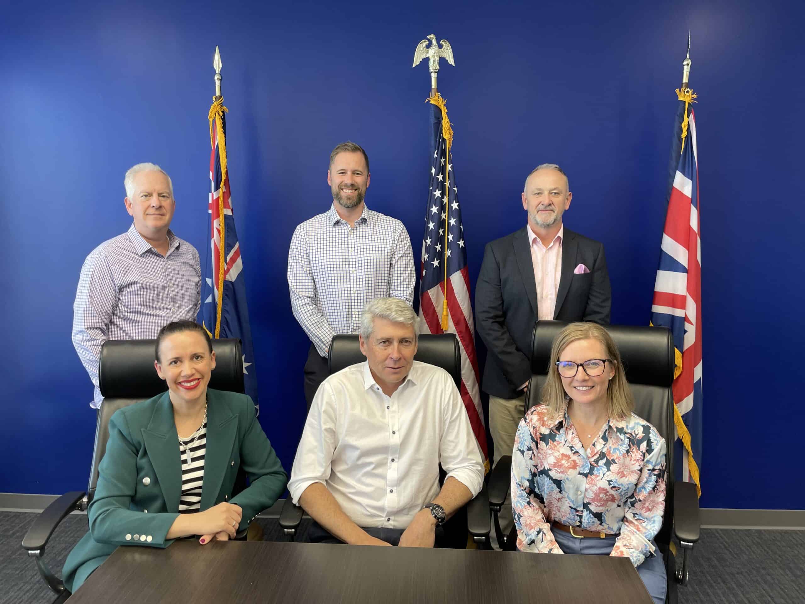 The executive team of H&B Defence in front of the flags of Australia